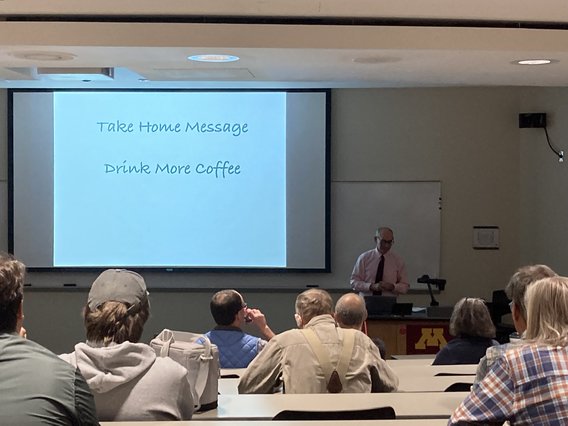 Nevin presents a slide that says "drink more coffee" at his event