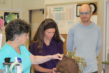 Grace, Jennifer, and Brett examine roots on a potted plant